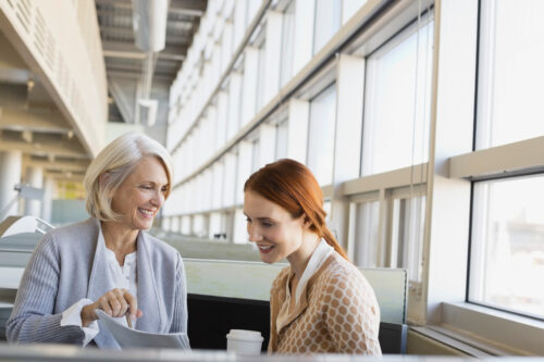 Older woman talks to young woman with red hair in an office