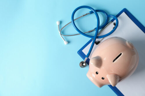 Stethoscope and piggy bank on blue background, space for text