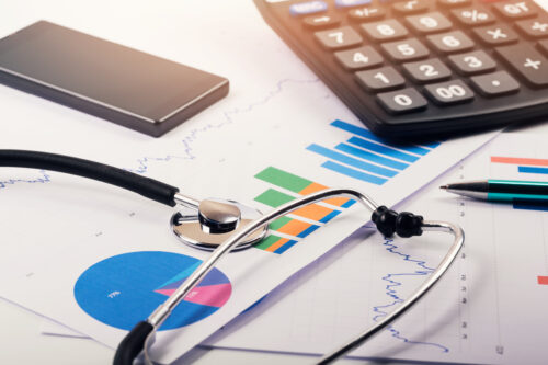 stethoscope resting on charts and in front of a calculator