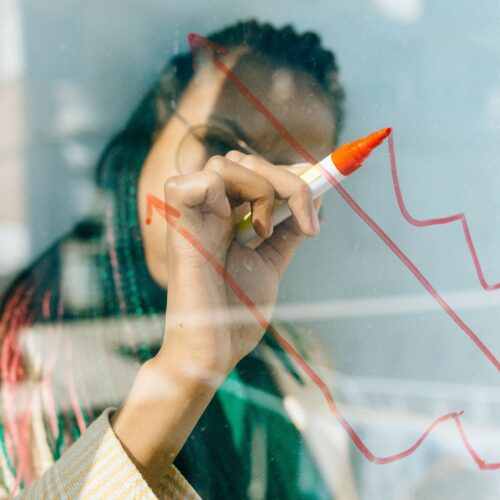 Woman drawing an upward chart trendline on glass