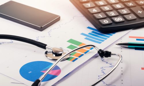 stethoscope resting on charts and in front of a calculator