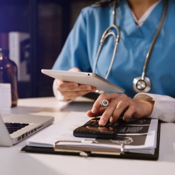 doctor with a calculator tablet and laptop