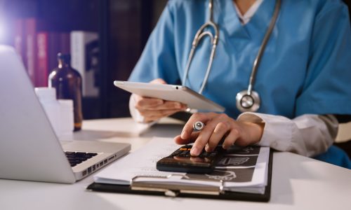 doctor with a calculator tablet and laptop