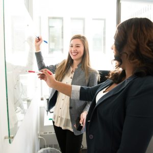 two women drawing on a whiteboard