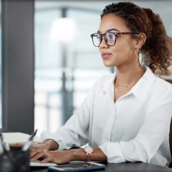 woman in a white blouse at a laptop typing