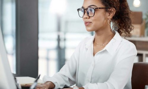 woman in a white blouse at a laptop typing