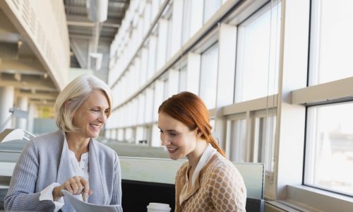 Older woman talks to young woman with red hair in an office