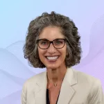 Portrait of a smiling woman with short gray hair and tortoiseshell glasses, wearing a beige blazer.