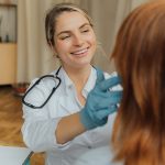 smiling woman doctor with gloves treats a patient