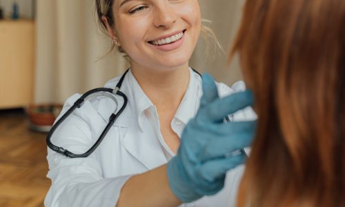 smiling woman doctor with gloves treats a patient