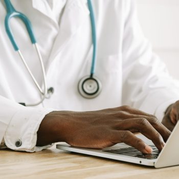 doctor wearing a stethoscope using a laptop