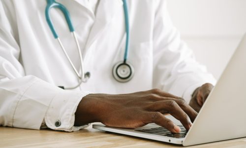 doctor wearing a stethoscope using a laptop