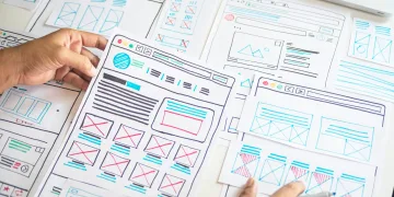 desk with hand drawings of web wireframes, hands in foreground